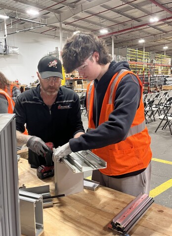 A man and a student look at a piece of equipment in an industrial setting. 